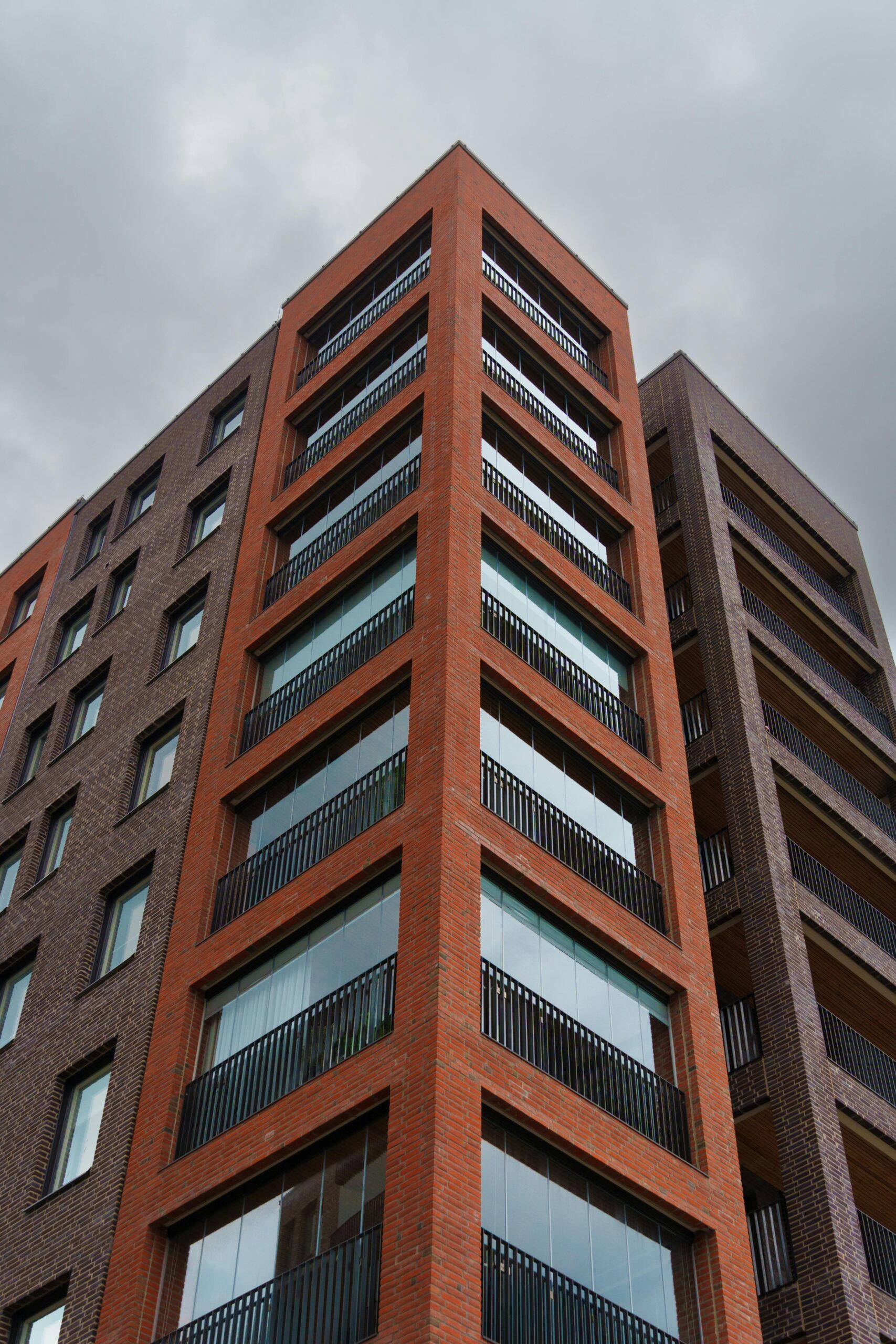 DOMŮ Low angle view of a modern apartment building against a grey sky.